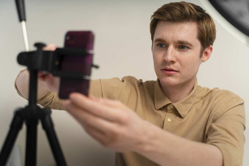 mężczyzna ustawiający aparat w telefonie na statywie